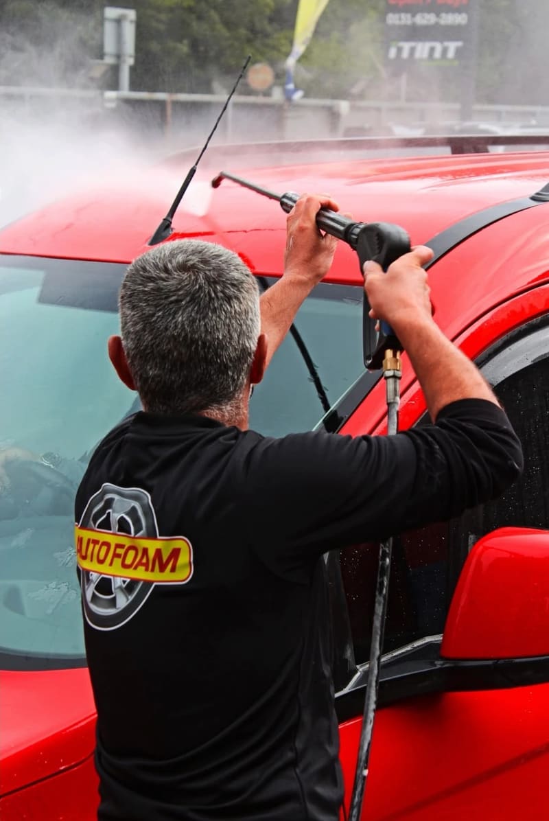 Pressure-washing a red car on the Autofoam forecourt