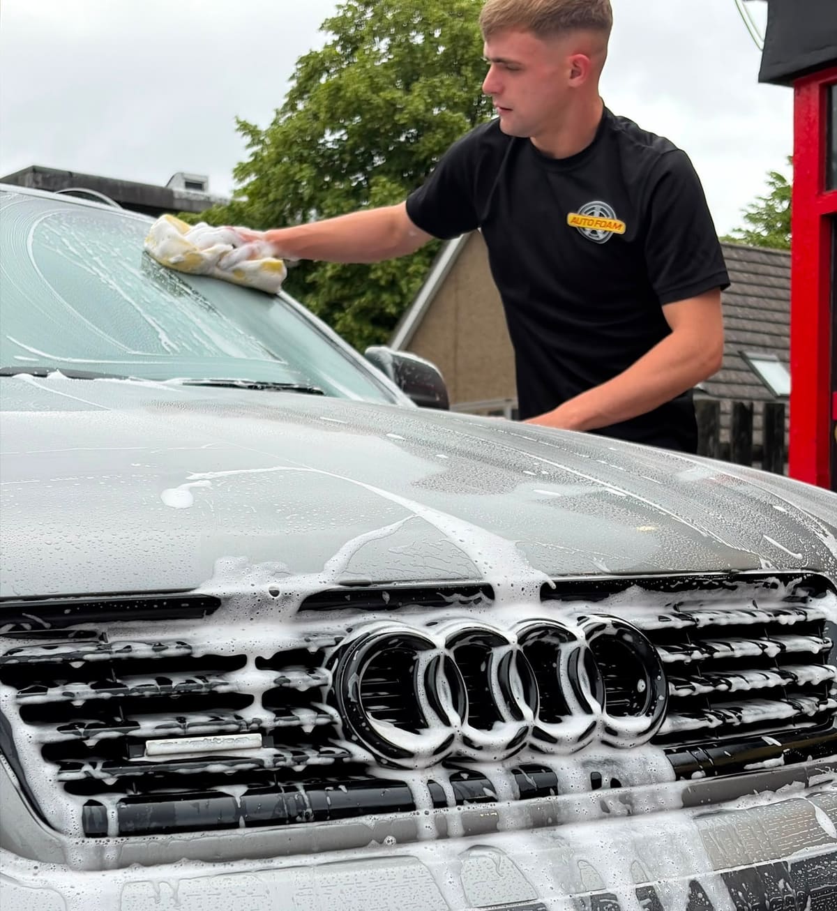 Hand-washing the windscreen and bonnet of a foam-covered Audi